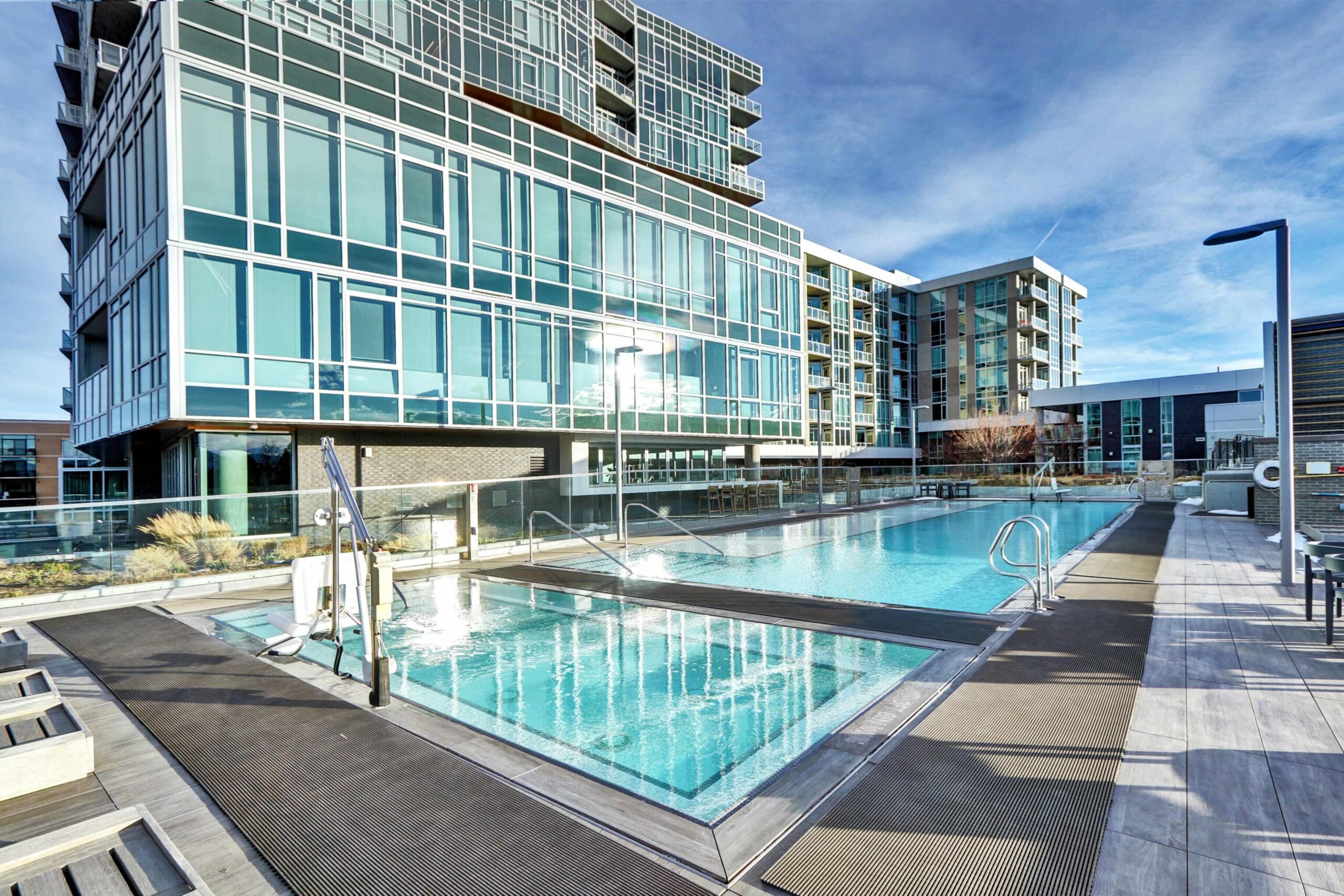 Resort-style outdoor heated pool at Lakehouse, surrounded by lounge seating and modern high-rise condos in Denver’s Sloan’s Lake district.