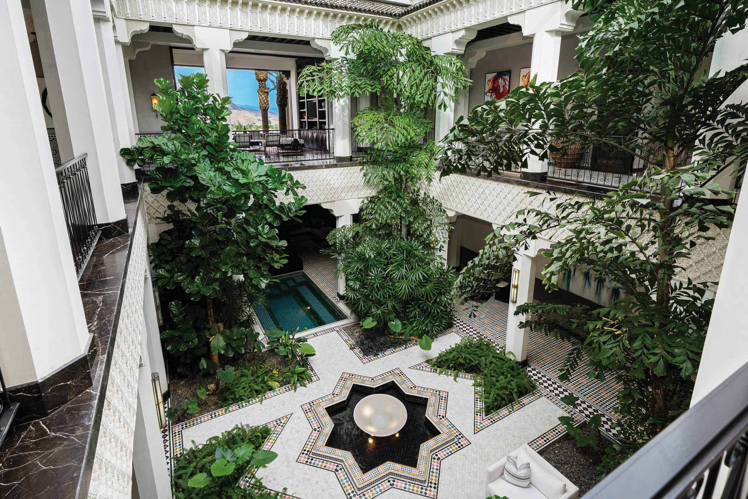 Interior and courtyard of Casbah Cove in Palm Desert, California—featuring ornate Moroccan arches, white columns, lush greenery, and an open-air courtyard with a central fountain.